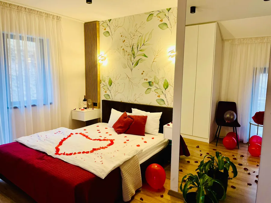 Romantic bedroom decorated with red rose petals and balloons